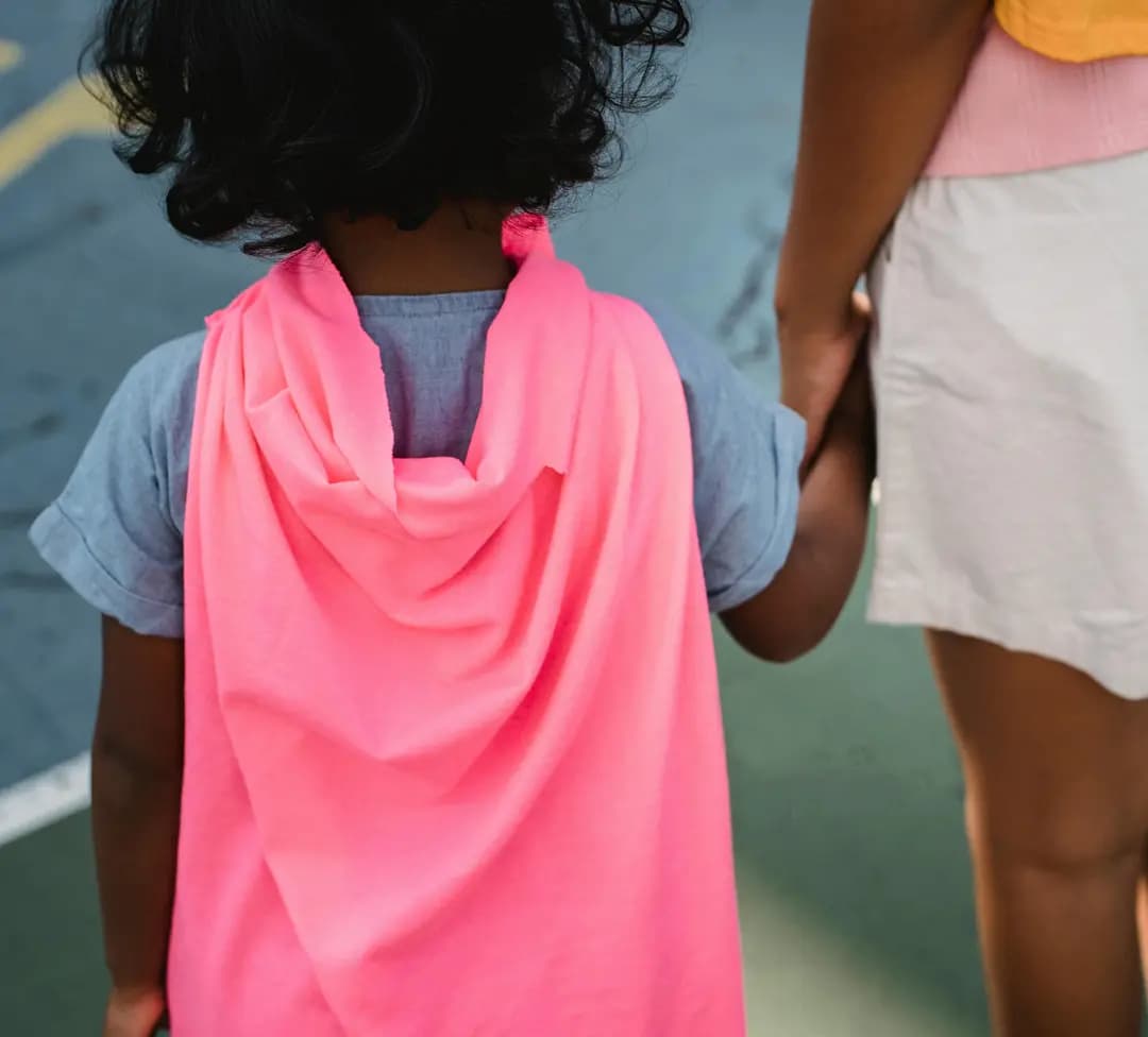 Un jeune enfant tenant la main d’un adulte en marchant à l’extérieur, symbole de protection, d’accompagnement et de soutien familial