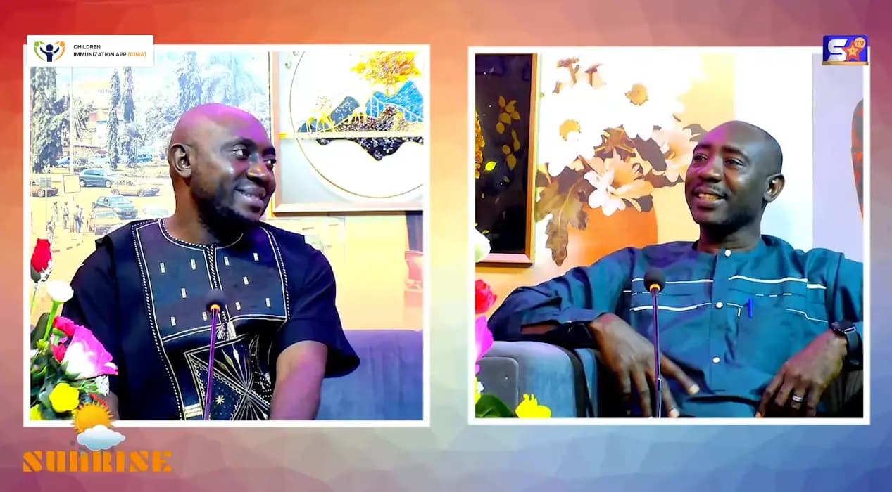 Two men in traditional attire engaged in an interview discussion on Children Immunization App's Sunrise program, featuring colorful background and floral decor