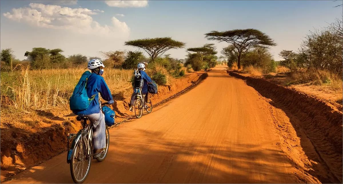 Two healthcare workers cycling on a hard road in South Sudan, helping in region vaccination.